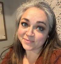 A woman with gray hair is smiling for the camera.