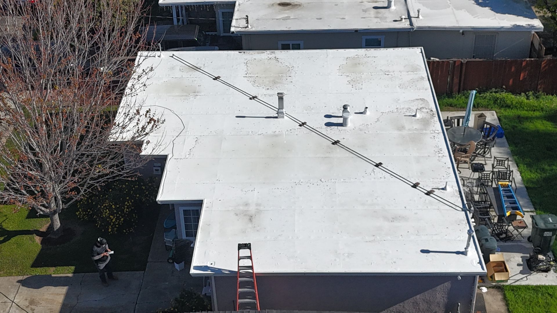 Overhead view of a flat white roof with ladder. 