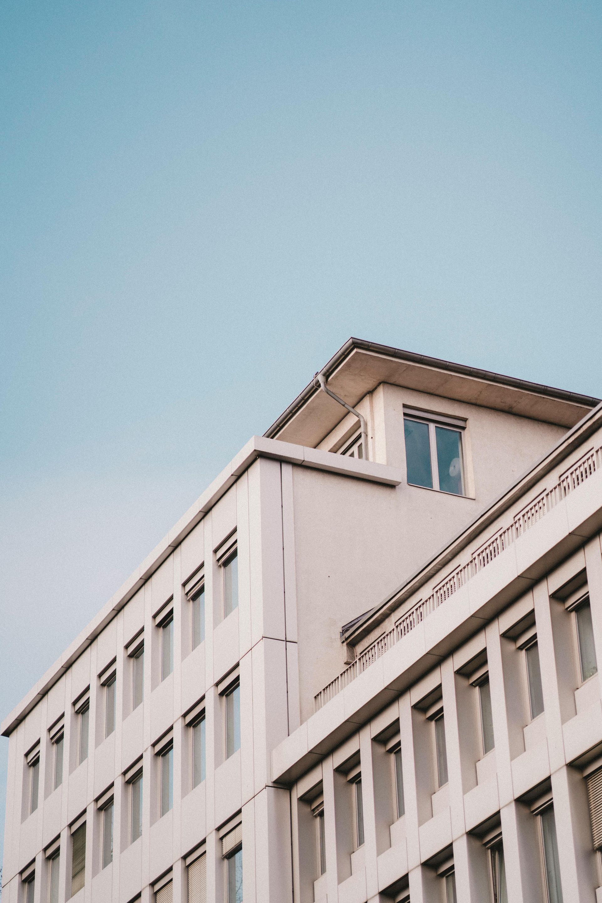White building against a blue sky, with many windows on the facade.