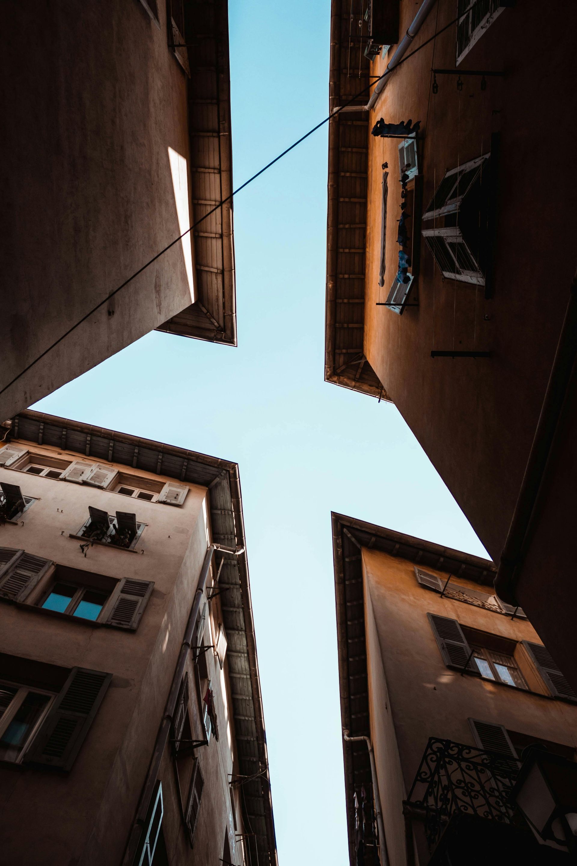 Looking up between buildings, seeing blue sky.
