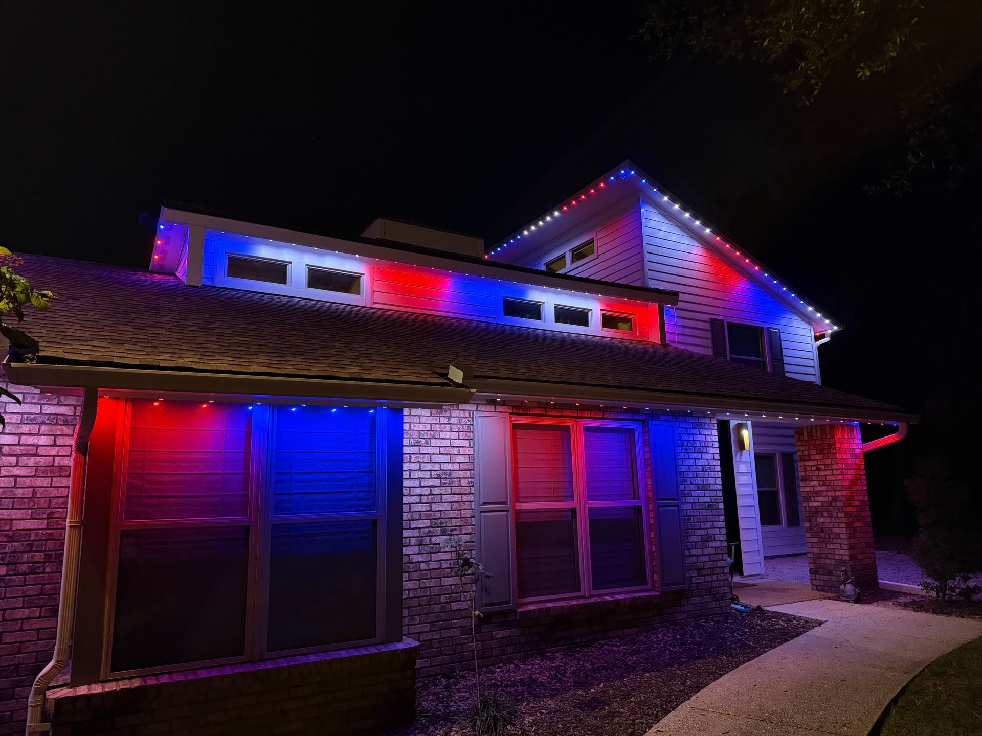 House decorated with red and blue lights for the night, with lights outlining the roof and windows.