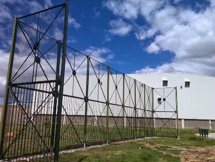 Una valla rodea un edificio con un cielo azul al fondo.