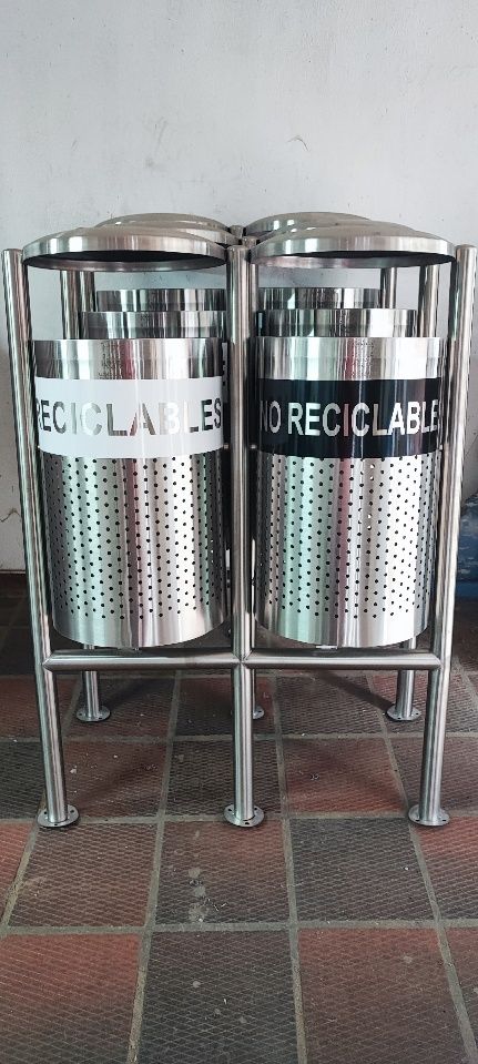 Dos botes de basura de acero inoxidable están uno al lado del otro sobre un piso de baldosas.