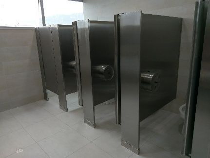 Una fila de cubículos de baño de acero inoxidable en un baño público.