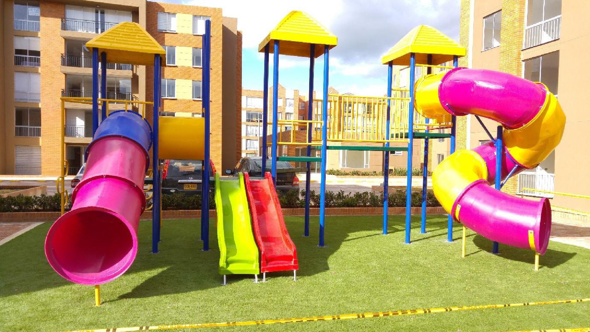 Un bote de basura de acero inoxidable está sobre una acera de ladrillos al lado de una calle.