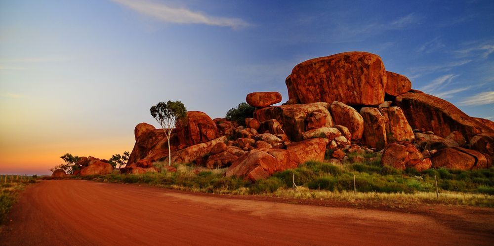 A Dirt Road Leading To A Large Rock Formation In The Desert — PK Crash Repairs In Tennant Creek, NT