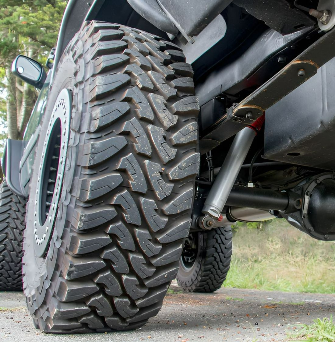 A Truck With A Large Tire Is Parked On The Side Of The Road — PK Crash Repairs In Ciccone, NT