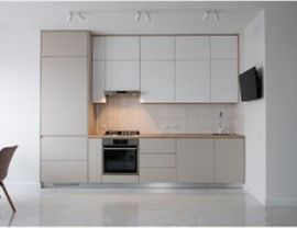 Modern kitchen with light cabinets, built-in appliances, and a small television on the wall.