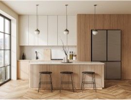 Modern kitchen with wood and white cabinetry, island with stools, and large refrigerator.