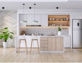 Modern kitchen with island, wooden floors, white cabinets, and light green pendant lights.