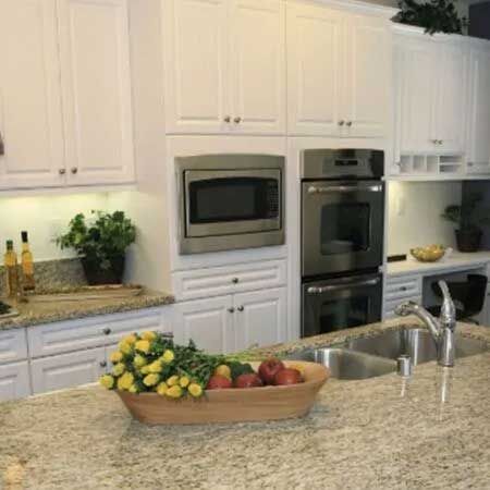 Kitchen with white cabinets, stainless steel appliances, and granite countertops. A bowl of fruit is on the counter.