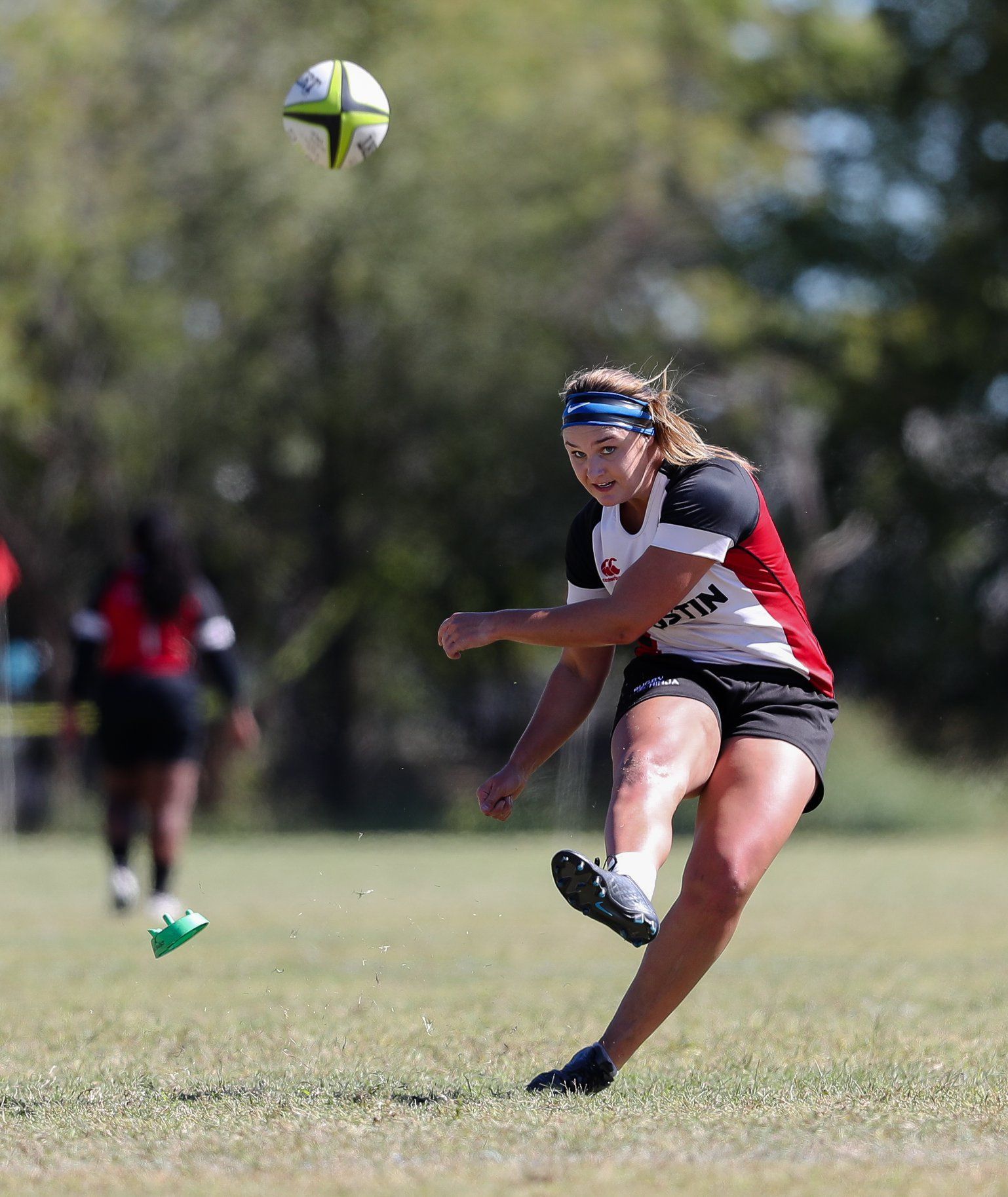 Athletic woman kicks rugby ball