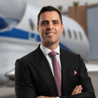 A man in a suit and tie is standing in front of an airplane.
