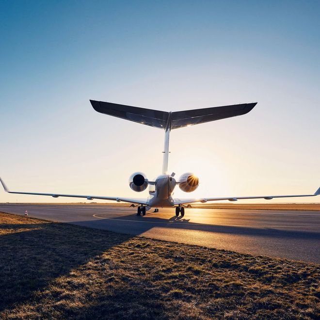 A small airplane is parked on a runway at sunset.