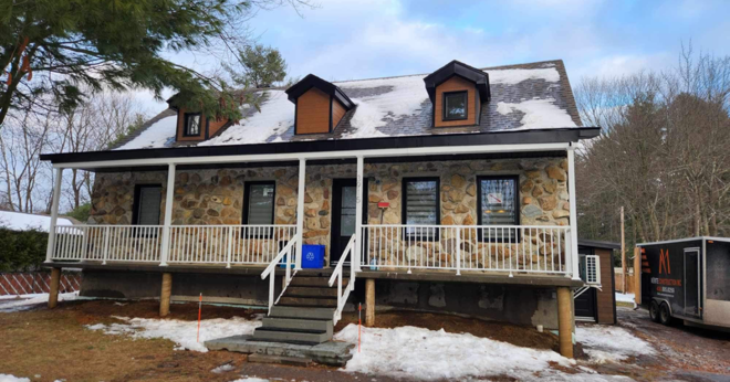 Une grande maison en pierre avec un porche et des escaliers dans la neige.