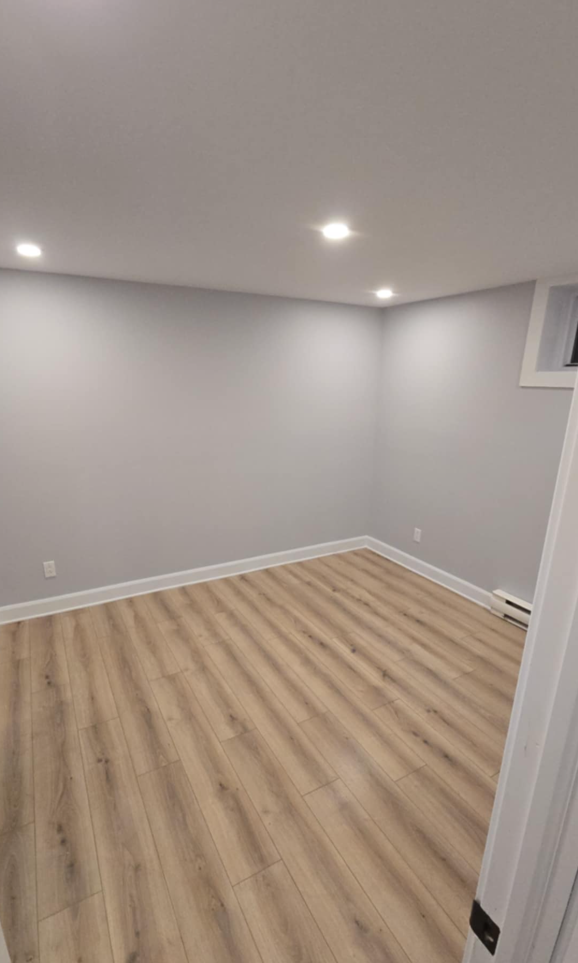 Une pièce vide avec du parquet et des murs blancs.