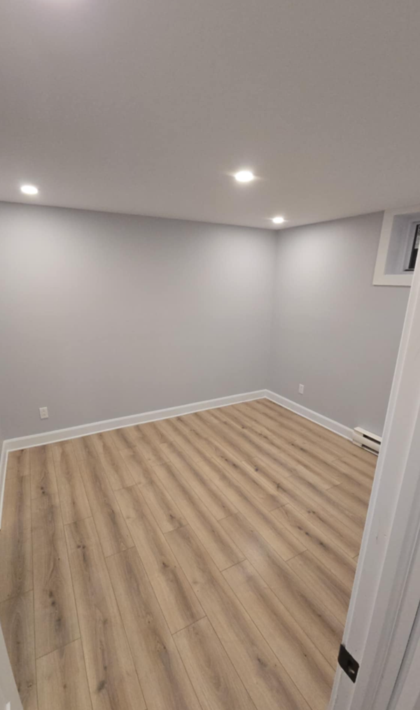 Un sous-sol vide avec planchers de bois franc et murs blancs.