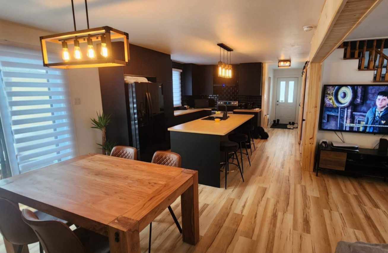 Un salon avec une table et des chaises en bois et une télévision à écran plat.