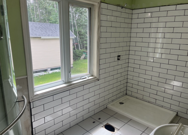 Une salle de bain avec carrelage blanc et une fenêtre.