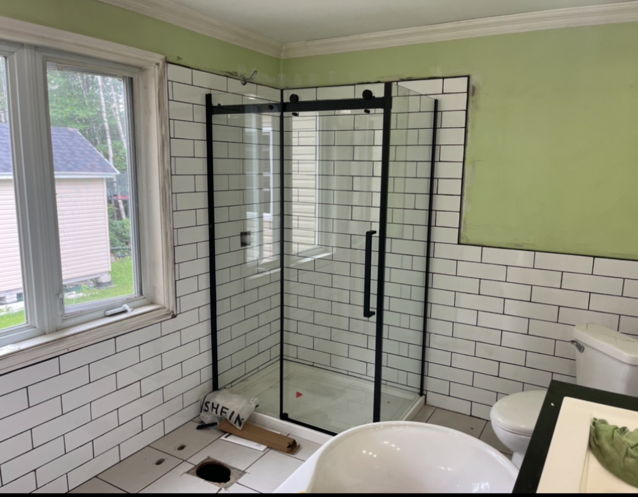 Une salle de bain avec du carrelage blanc et une porte de douche coulissante en verre
