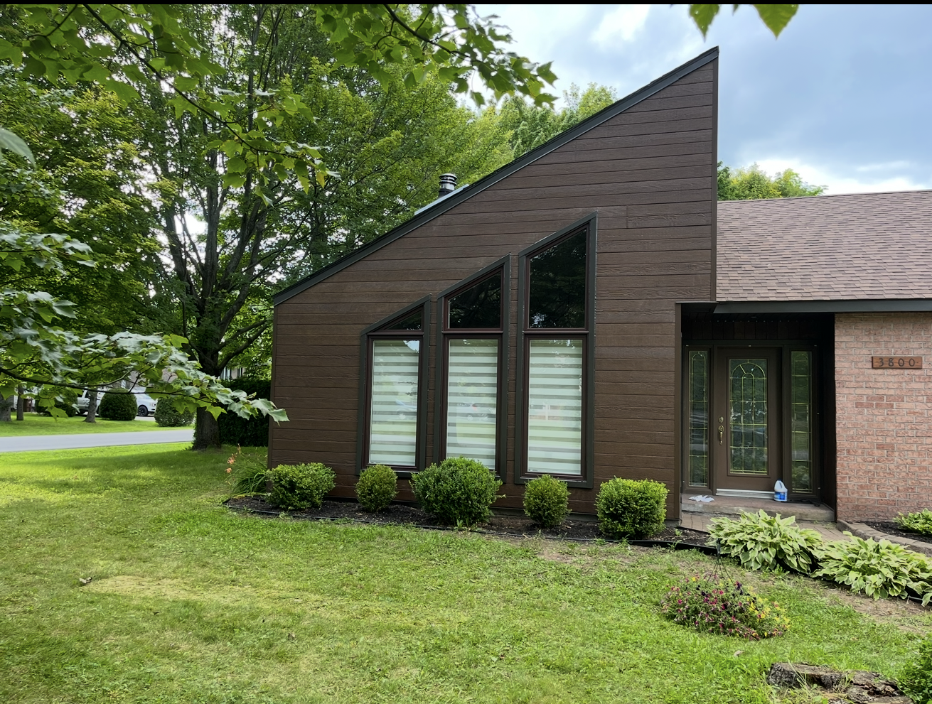 Une maison en briques avec un toit en pente et beaucoup de fenêtres