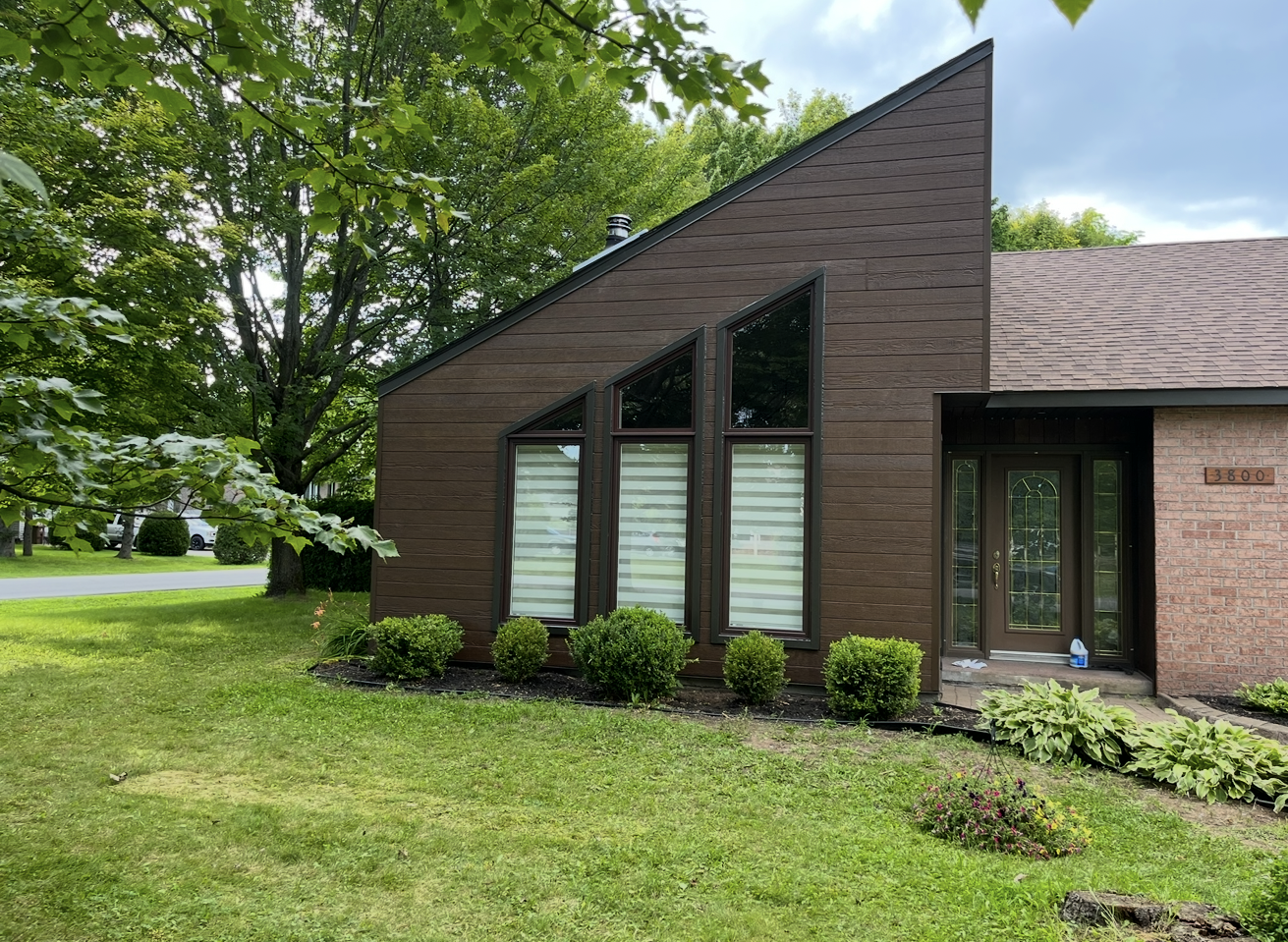 Une maison en briques avec un toit en pente et beaucoup de fenêtres.