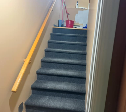 Un escalier avec une rampe jaune et une serpillière rouge