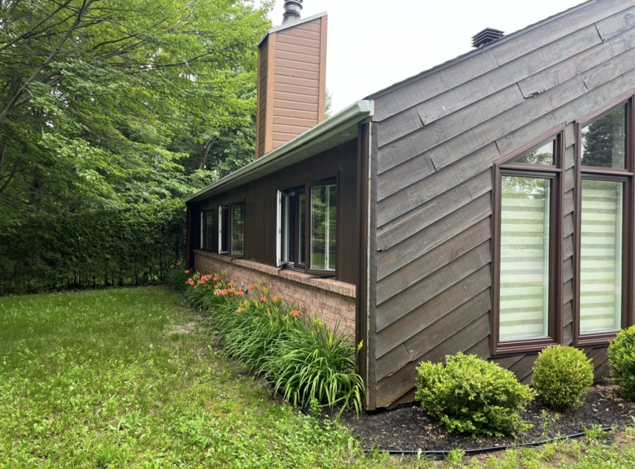 Une maison avec beaucoup de fenêtres et une cheminée sur le côté.