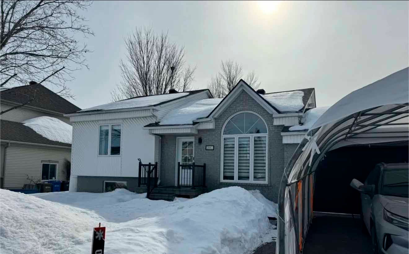 Une voiture est garée devant une maison couverte de neige.