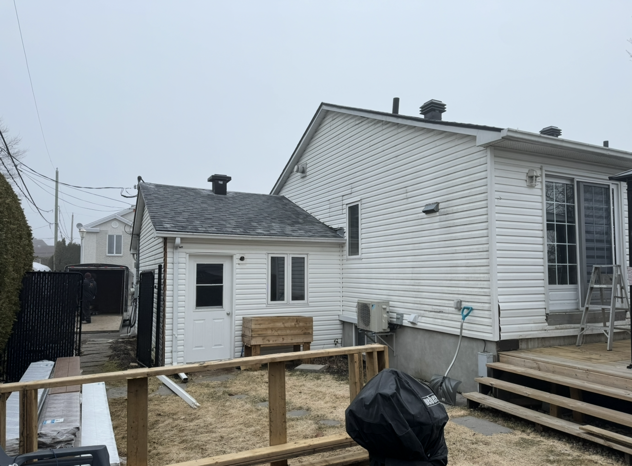 Une maison blanche avec un toit noir est en cours de rénovation.