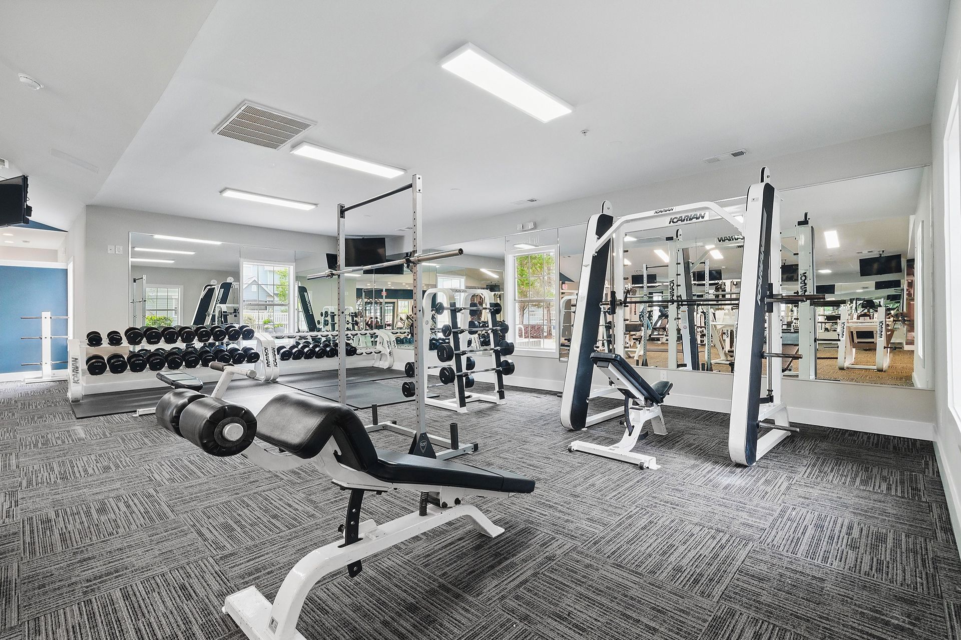 A gym with a variety of equipment including dumbbells, weight machines, and a bench press.