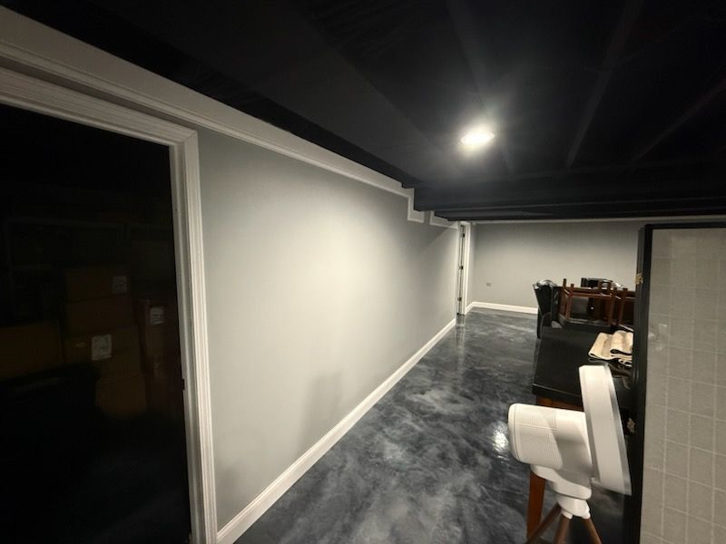 Long hallway with gray walls, white trim, and a black ceiling. The floor is a dark, glossy, epoxy finish.