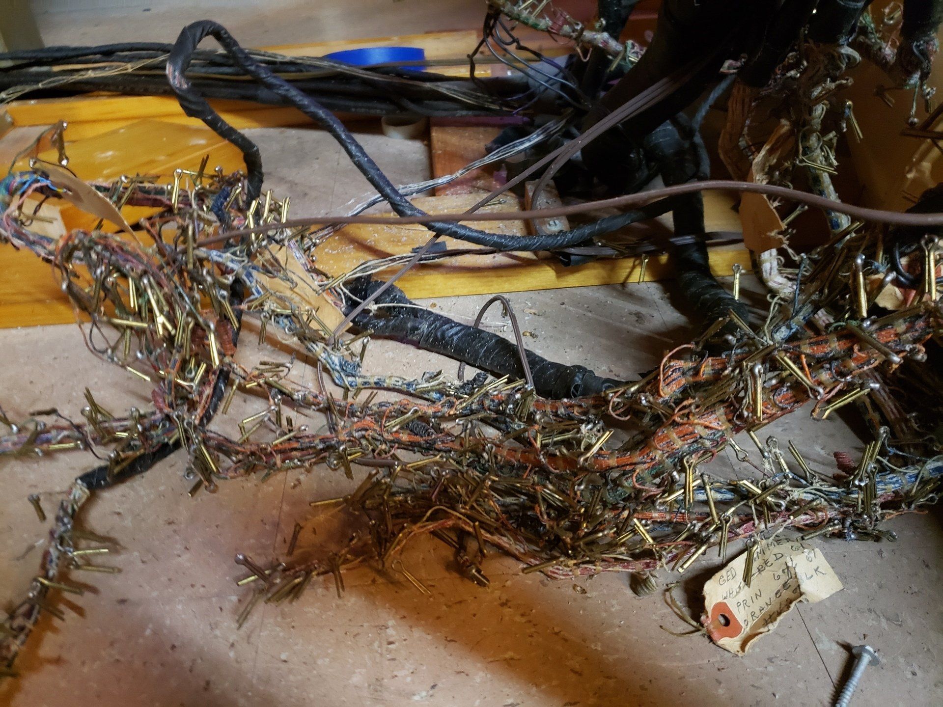 Tangled mass of wires with brass connectors, some charred, on a wooden surface, likely electrical damage.