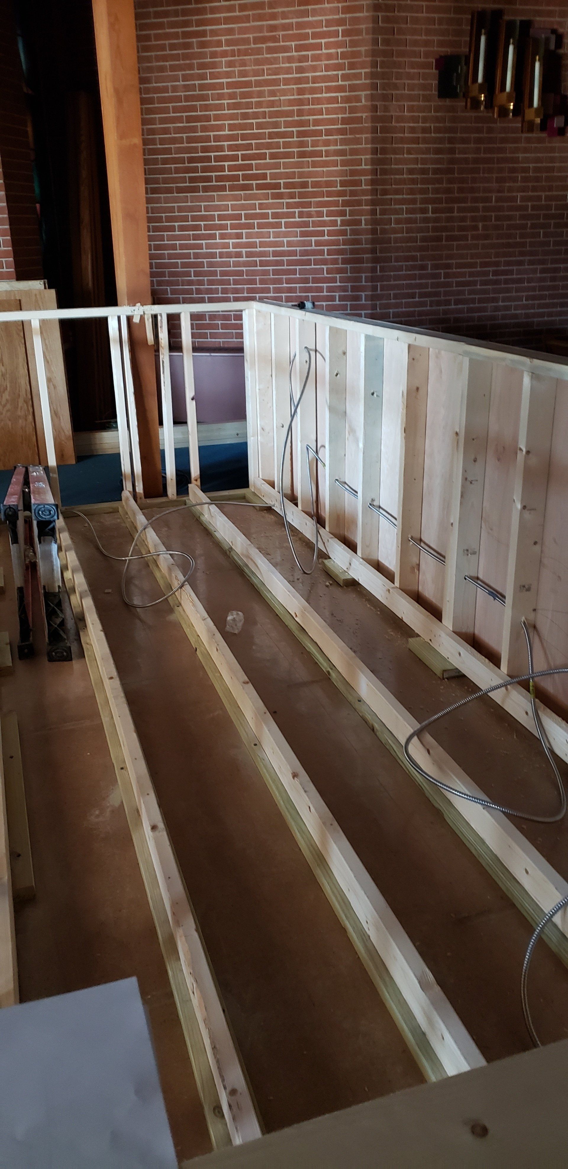 Interior of a building under construction, with wood framework and brick wall in the background.