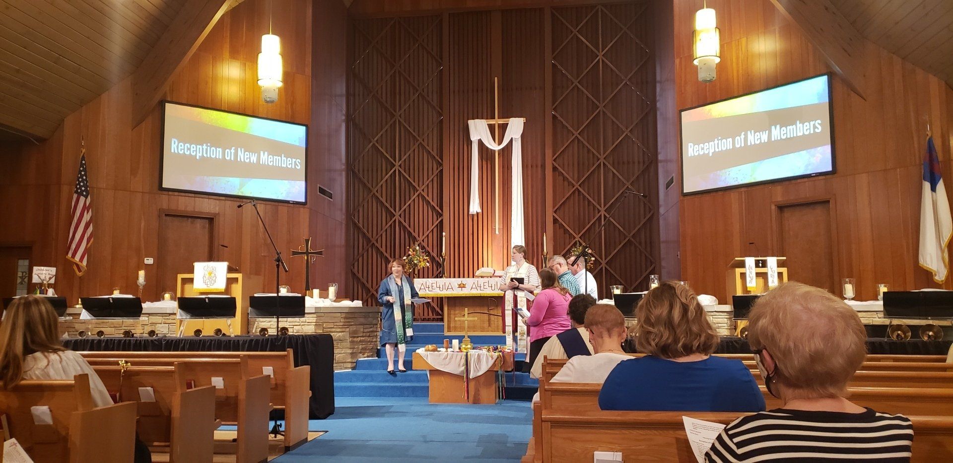 Interior of a church during a service, people seated. A screen says 