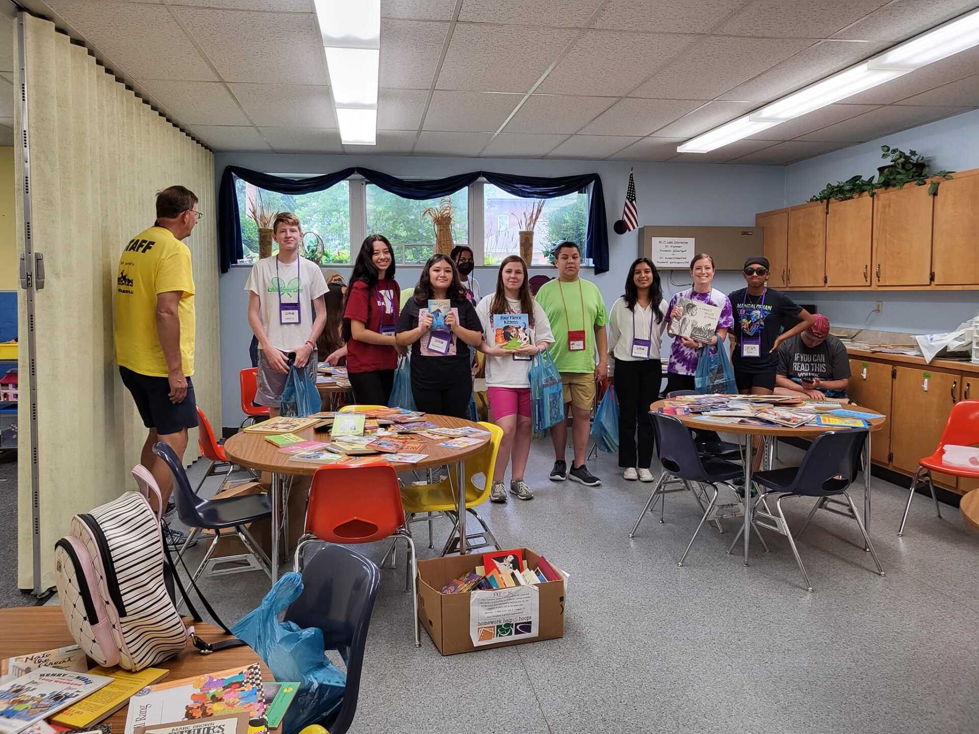 Group of people in a classroom setting, with books and materials.
