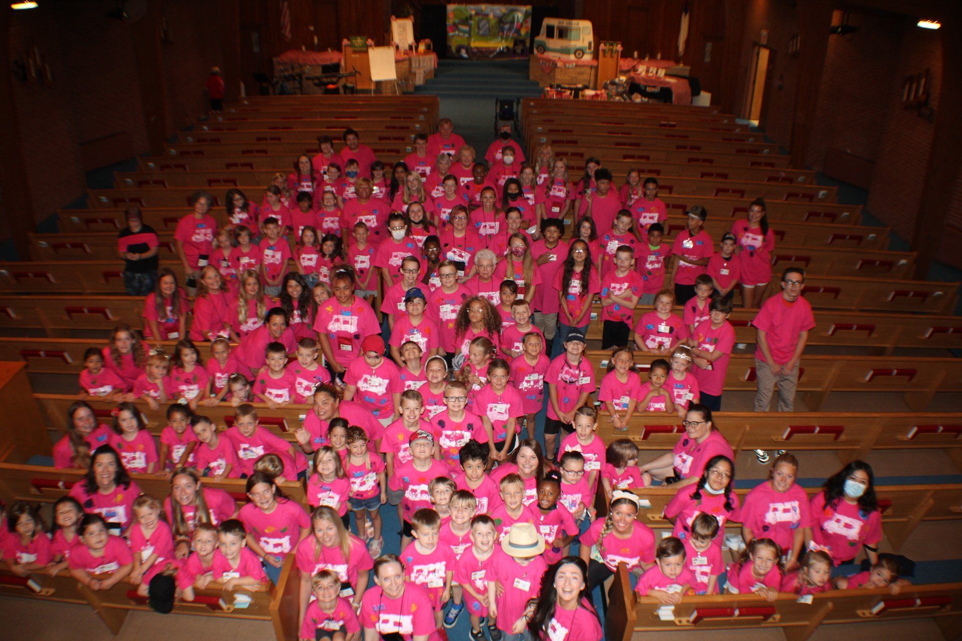 Large group of people in pink shirts posing in a church.