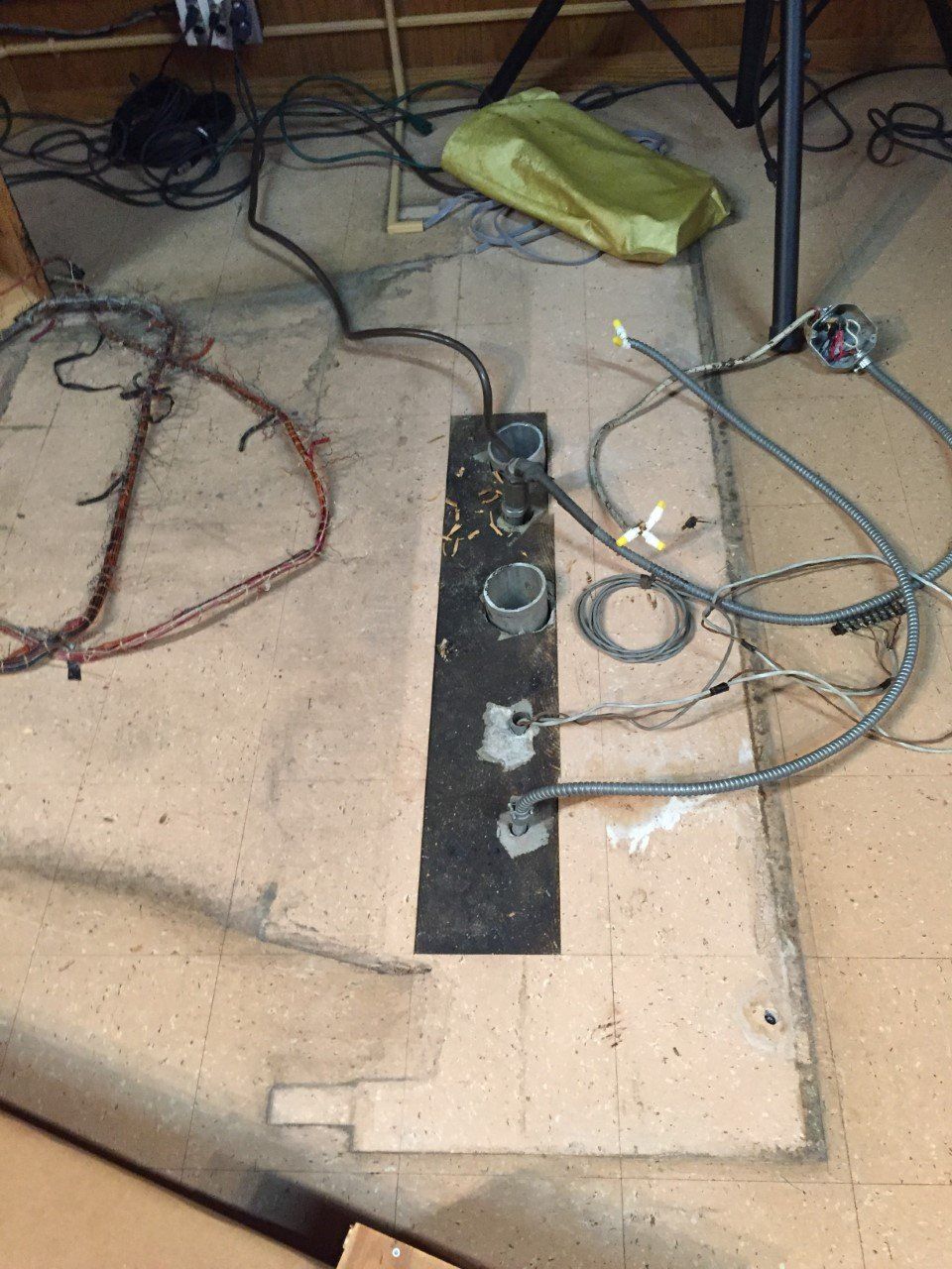 Messy room floor with exposed wires, a black metal plate, and electrical outlets.