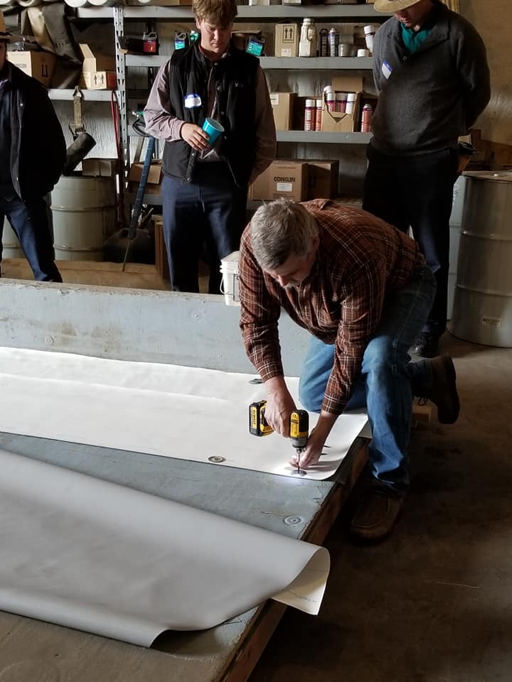 a man installing a piece of fabric on a roof panel