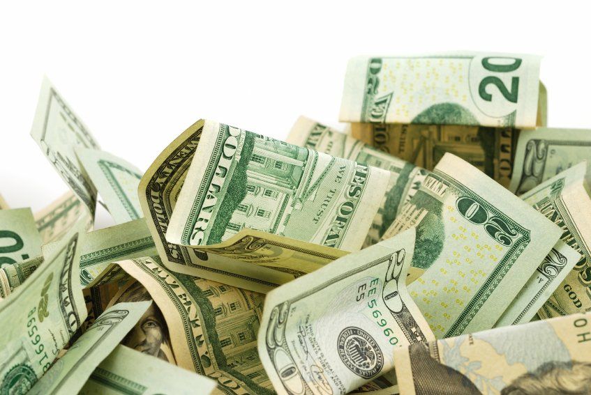A fan of U.S. dollar bills, primarily $5 and $1, held against a white background.