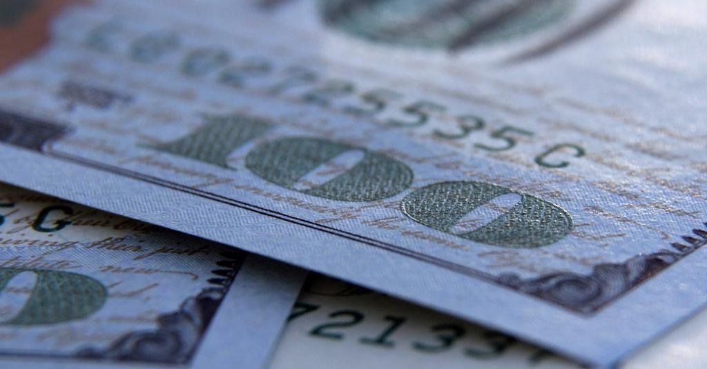 Close-up of US $100 bills, showing serial numbers and