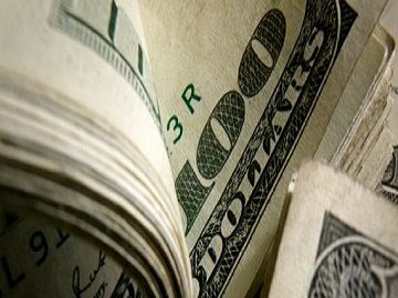 Close-up of a stack of US $100 bills, showing detail of paper texture and green ink.