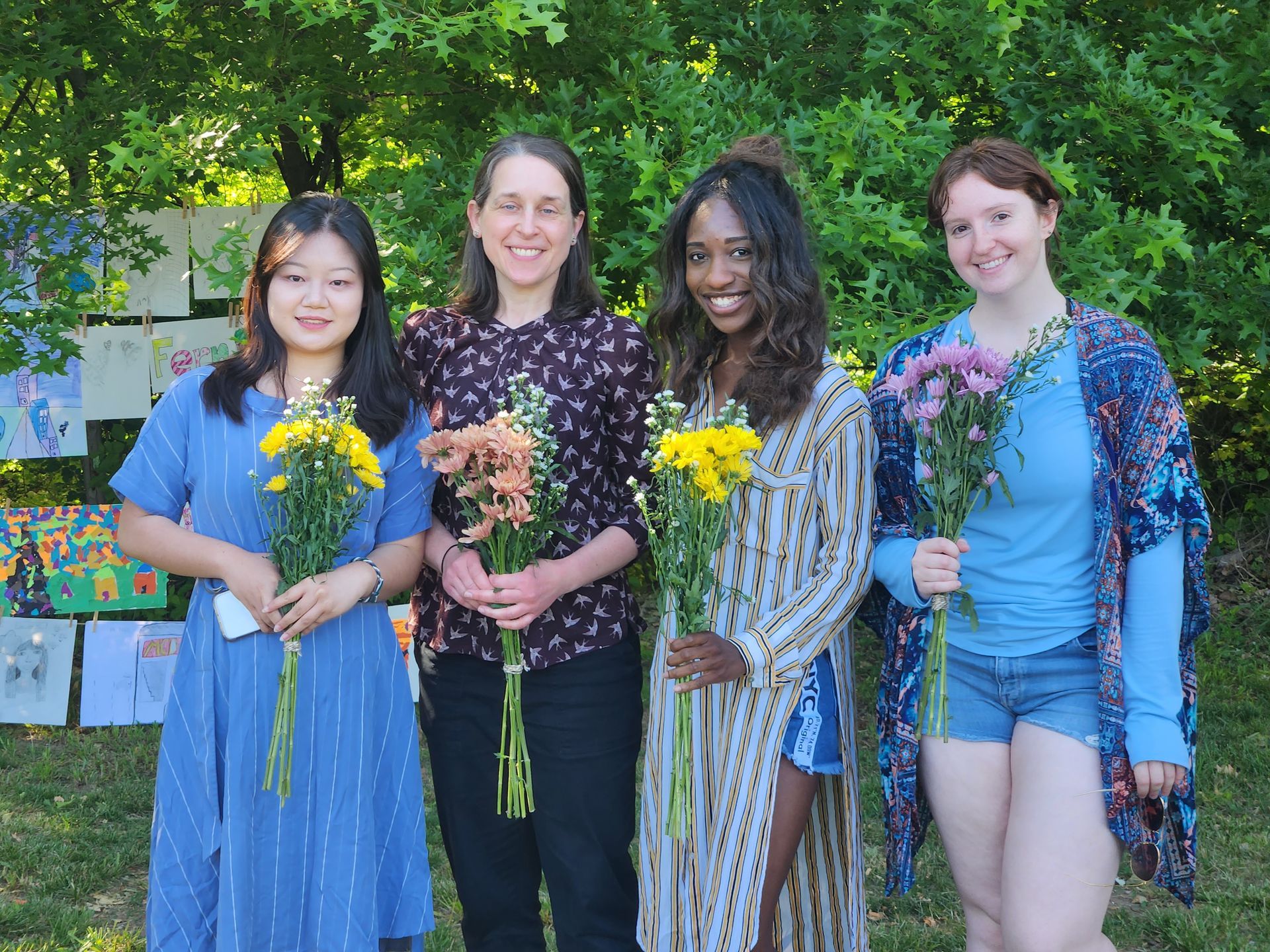 Four women are standing next to each other holding bouquets of flowers.