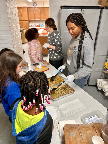 A group of people are standing around a table preparing food.