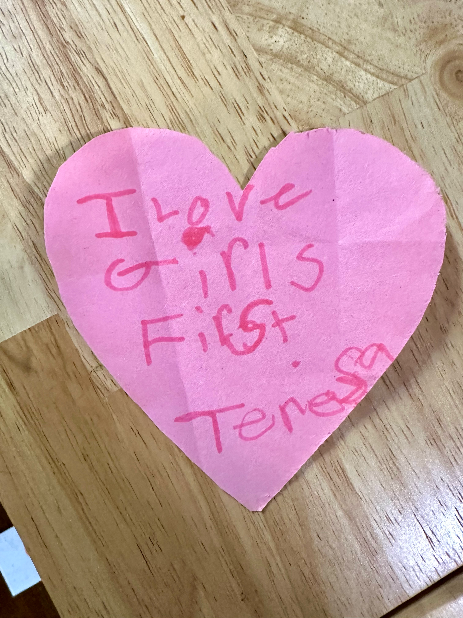 A pink heart shaped note that says i love girls first teresa