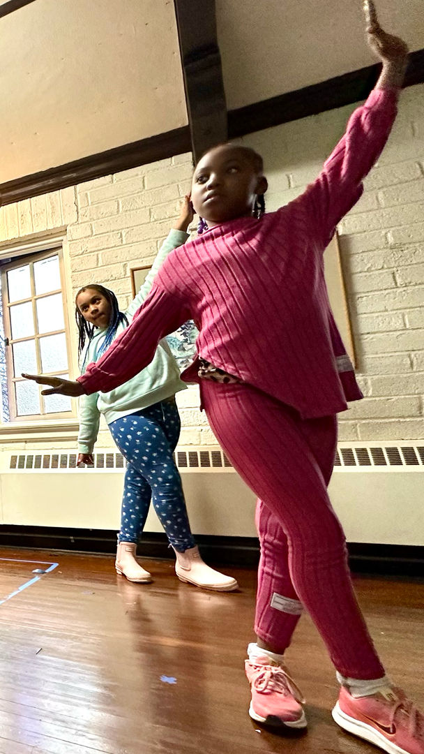 Two young girls are dancing in a dance studio.