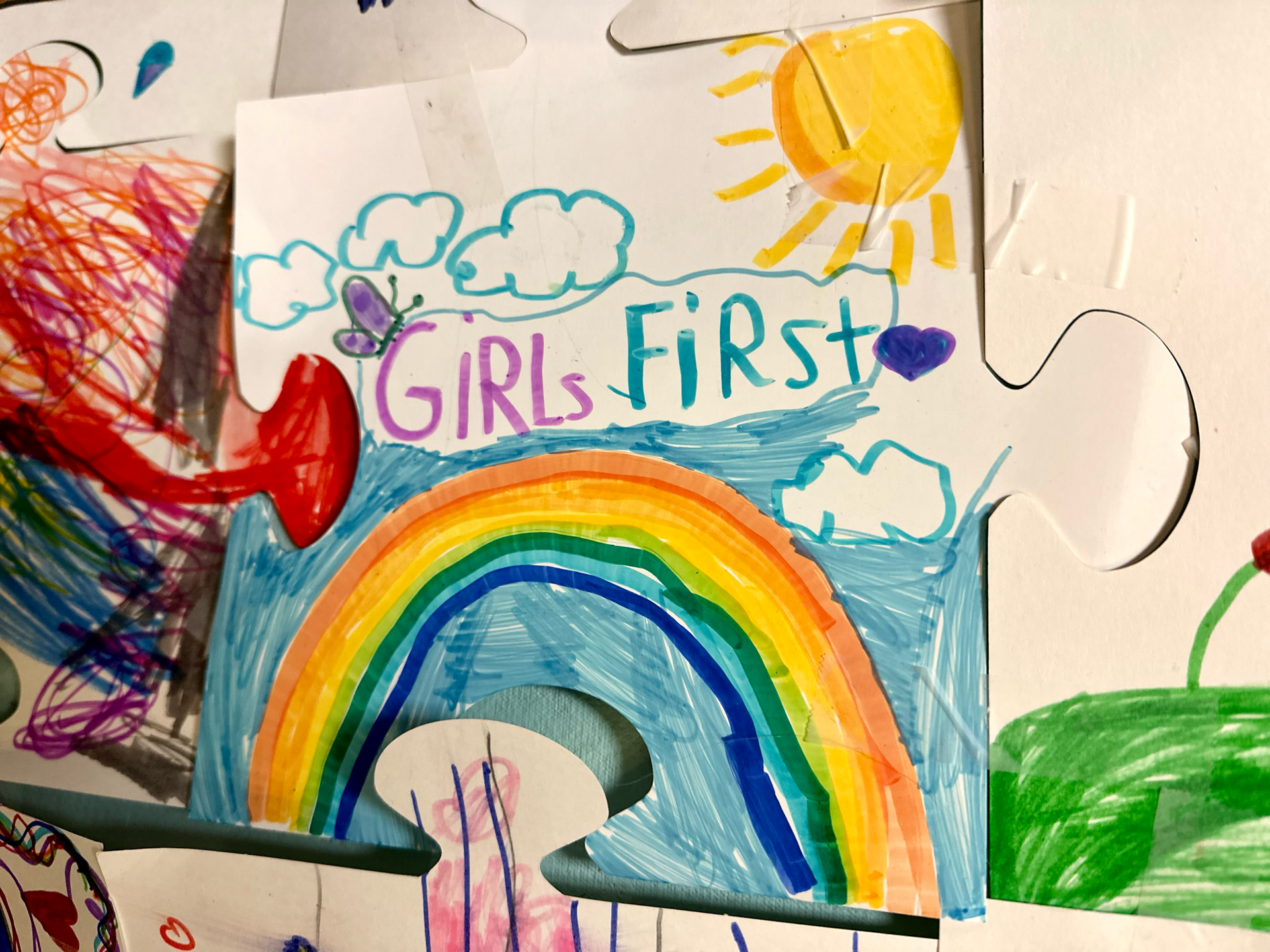 A child 's drawing of a rainbow and the words girls first
