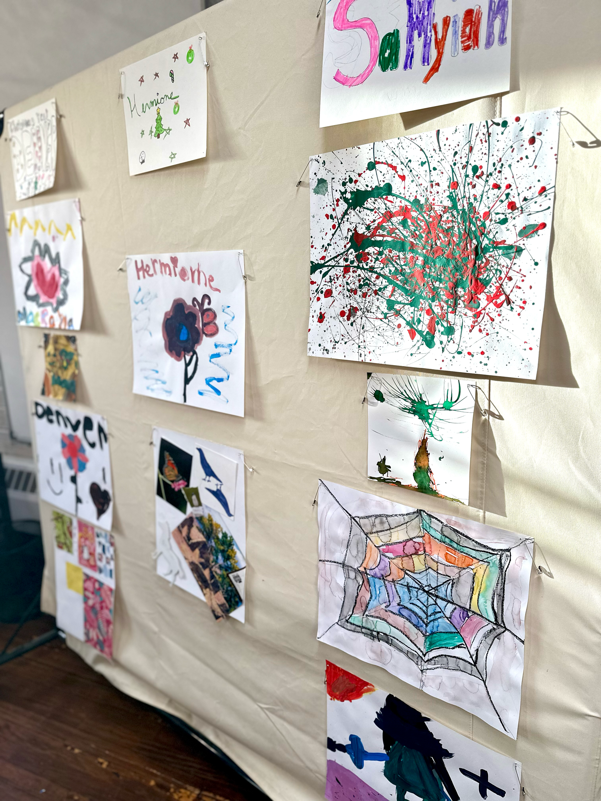 Children 's drawings are displayed on a wall with a sign that says sallysam