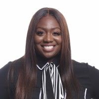 A woman with long hair is smiling and wearing a black and white shirt.