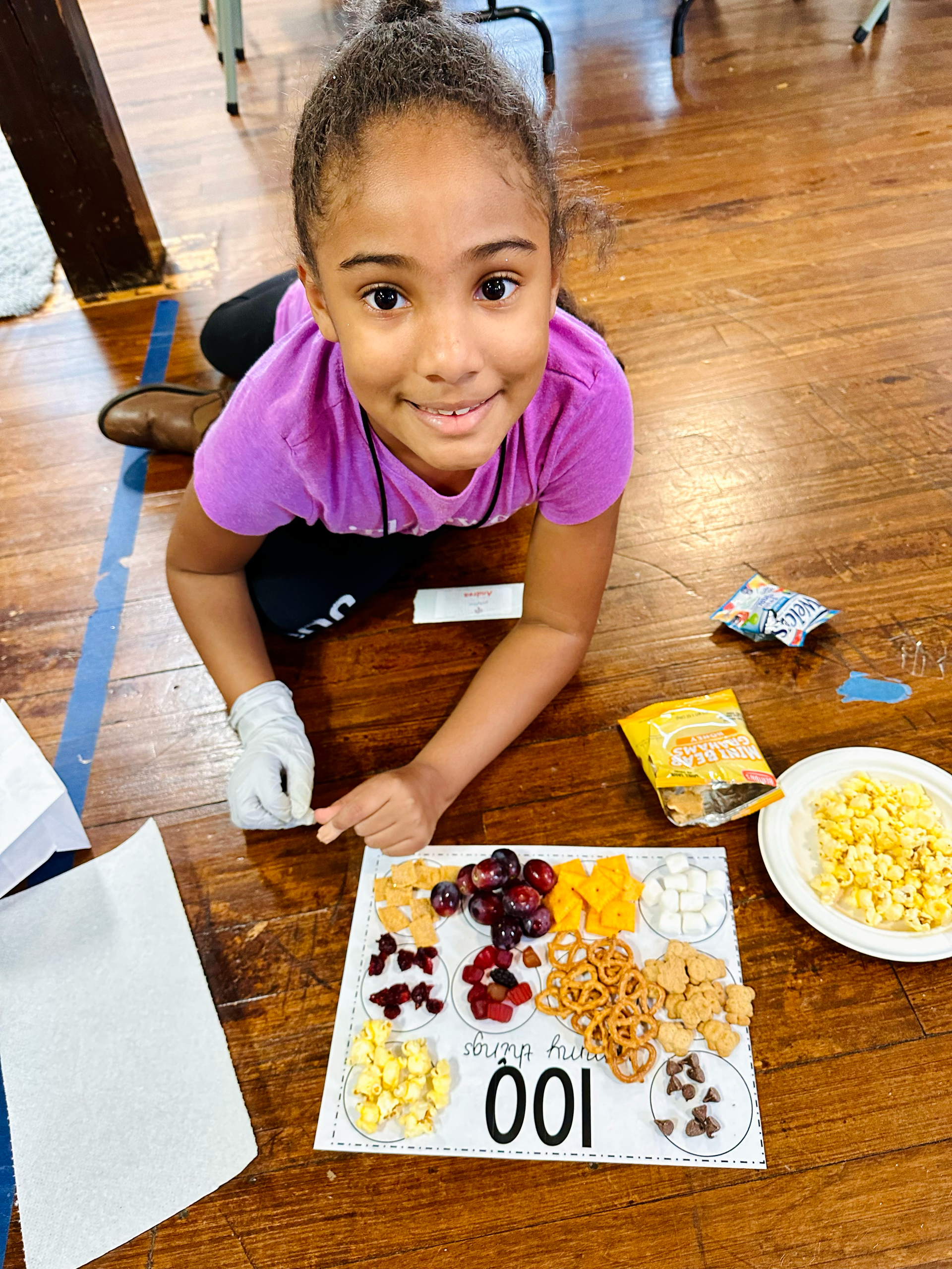 A young girl is laying on the floor with a plate of food.